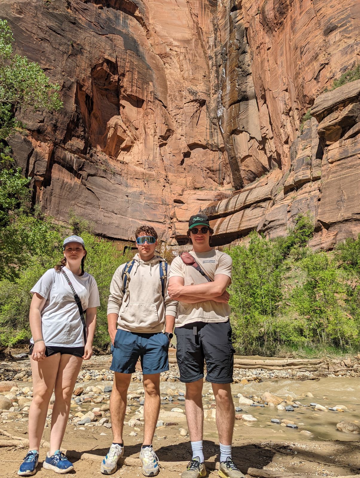 Three hikers in front of a red sandstone canyon wall