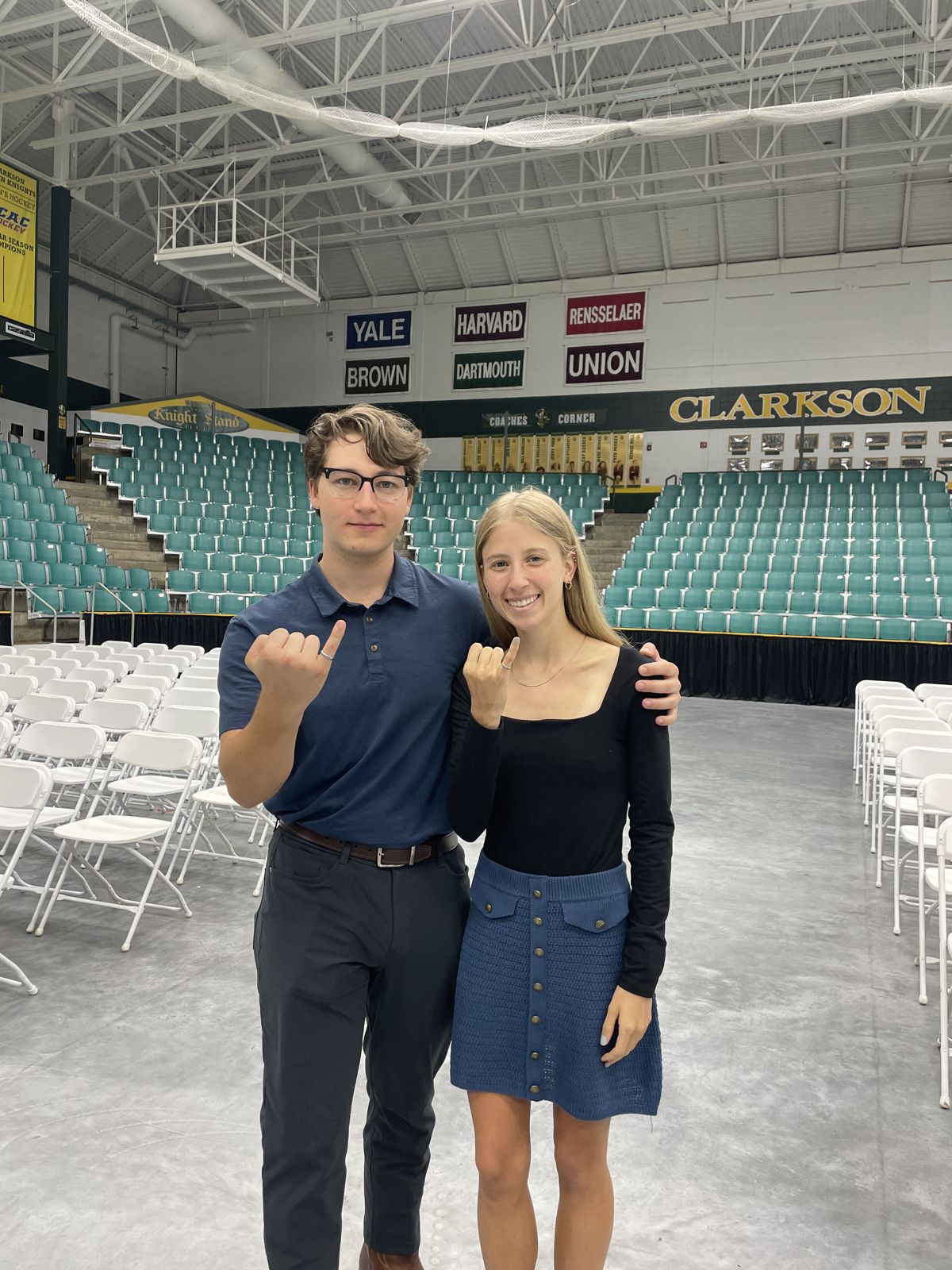 Two people showing class rings inside the Clarkson arena