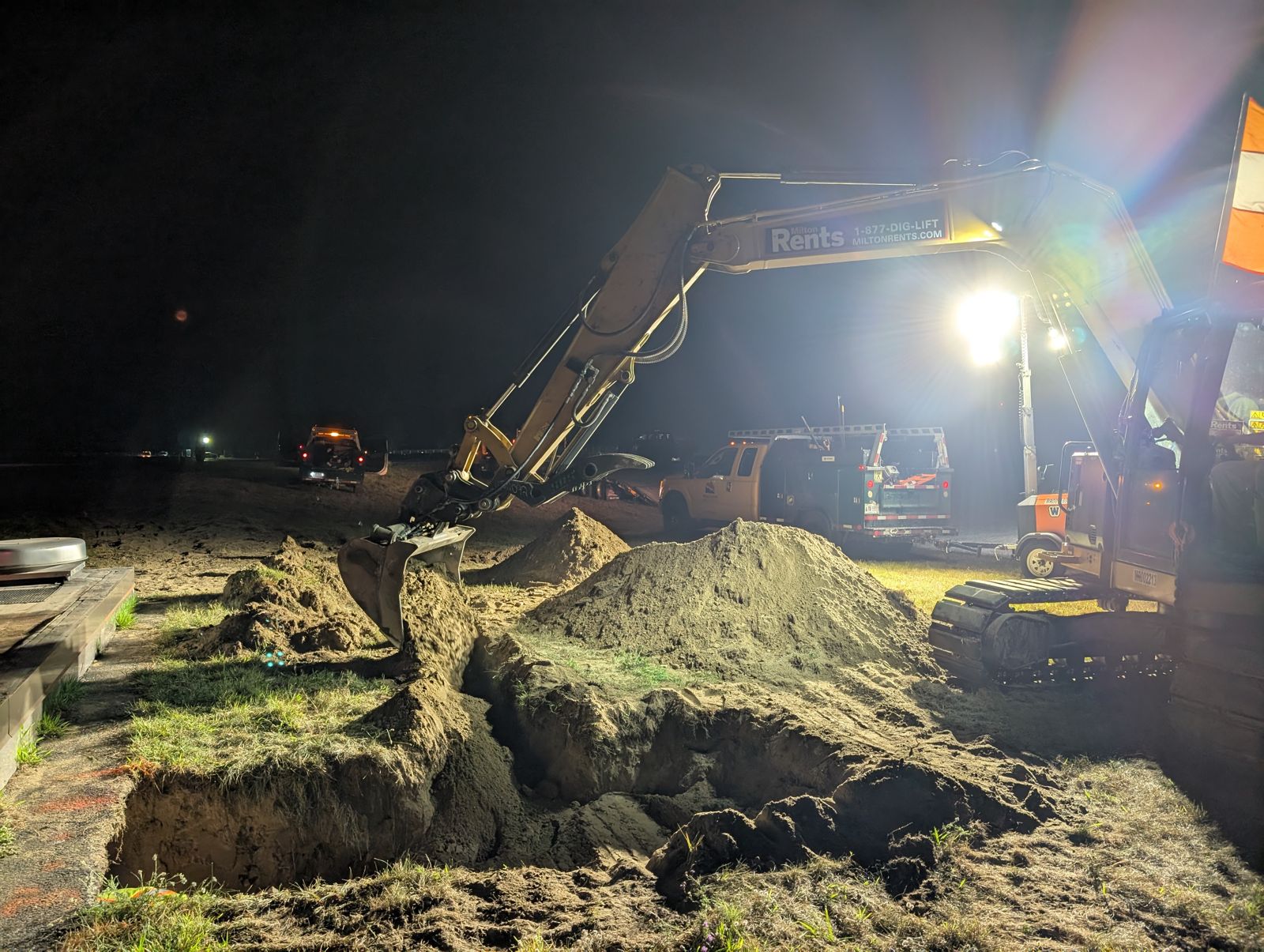 Excavator digging under a light tower at night