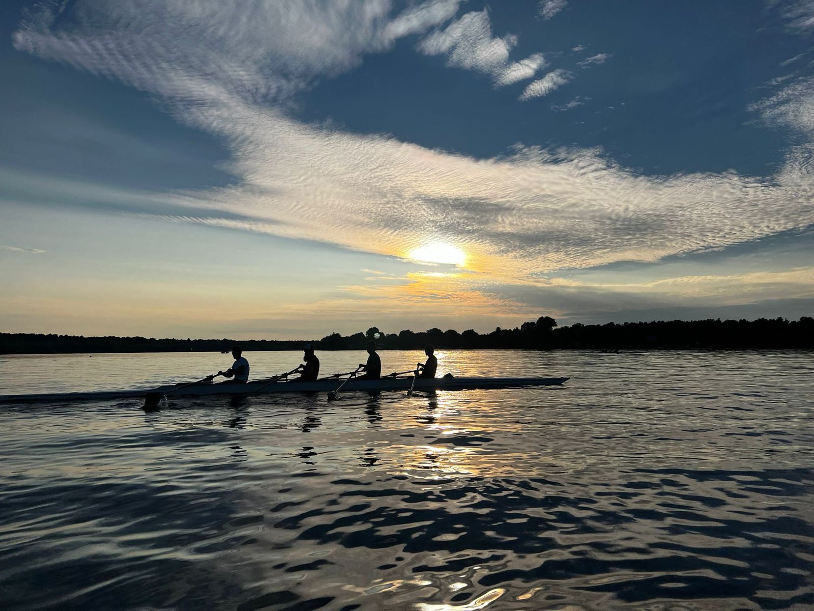 Four rowers silhouetted against a sunset