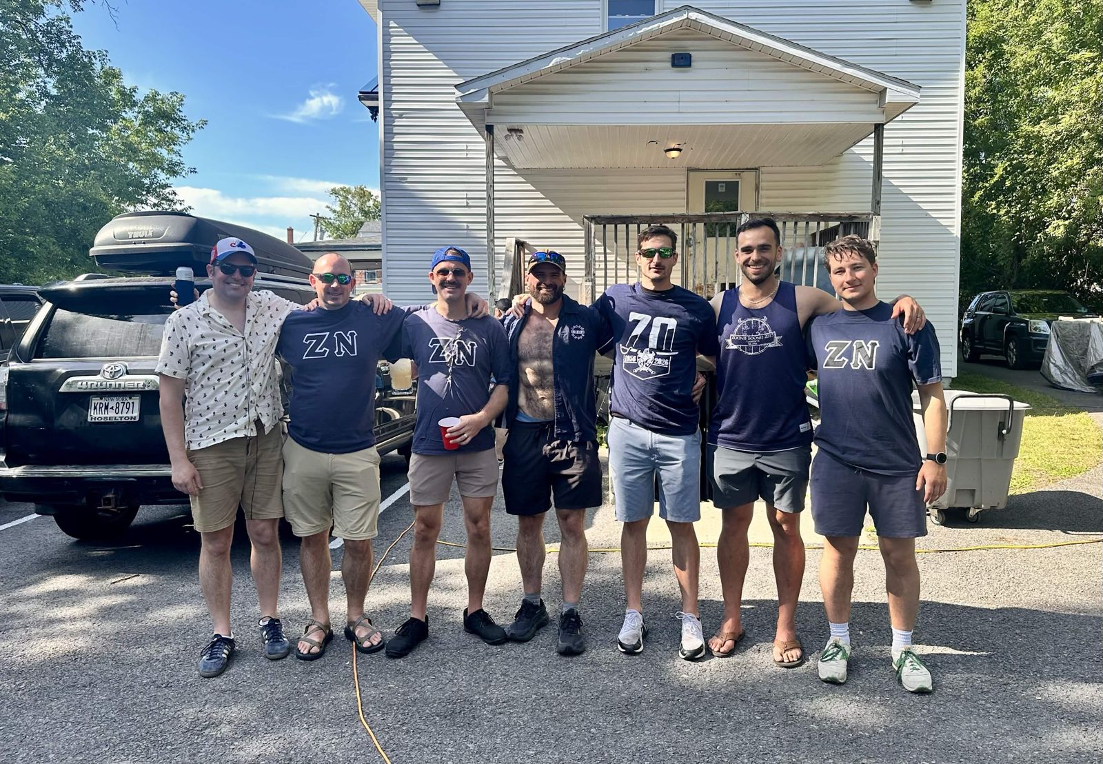 Group of Zeta Nu brothers in front of a white house